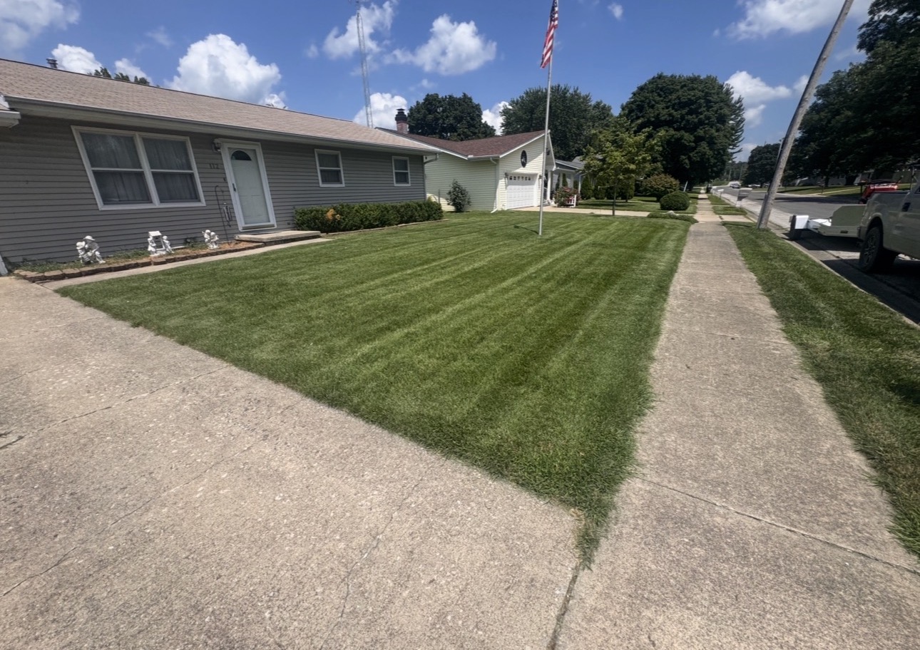 Front yard with crisp mowing stripes and flag pole